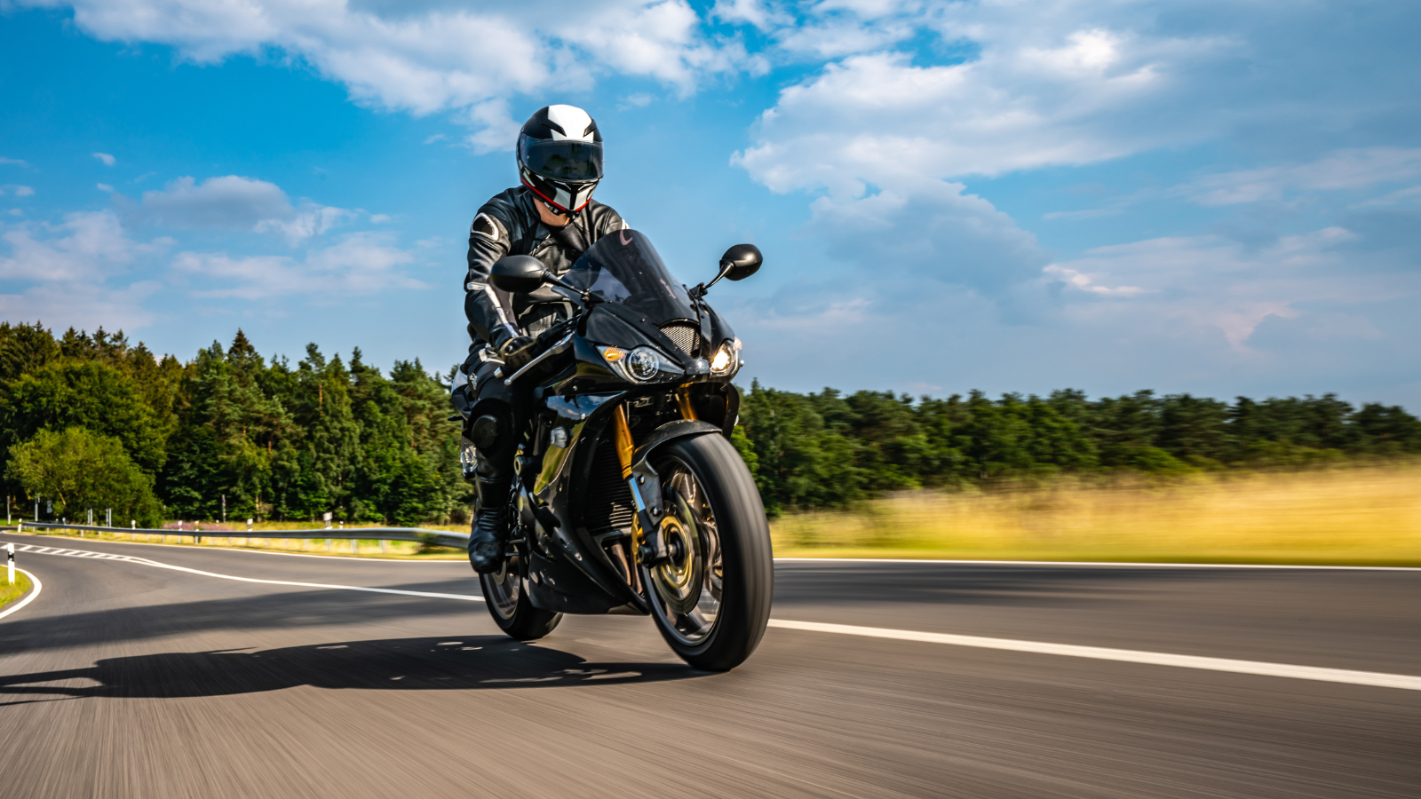 Someone riding a motorcycle on a road against a blue sky.