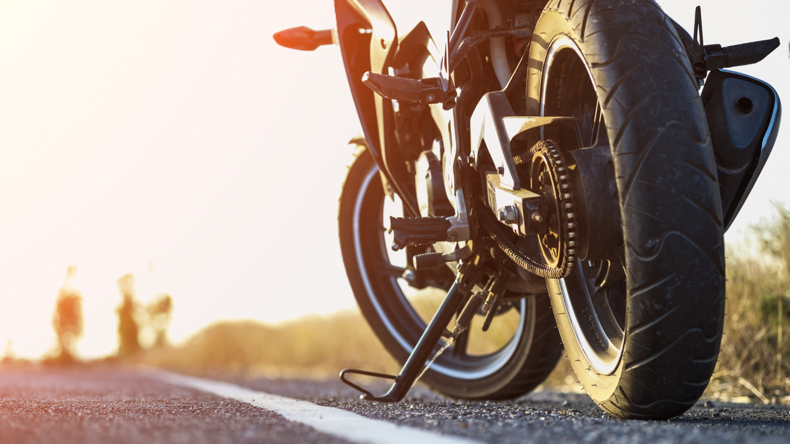A motorcycle driving down a road at sunset.
