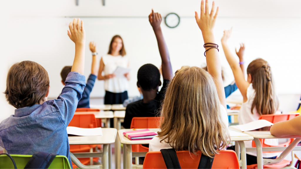 Kids raise hands in their international school classroom