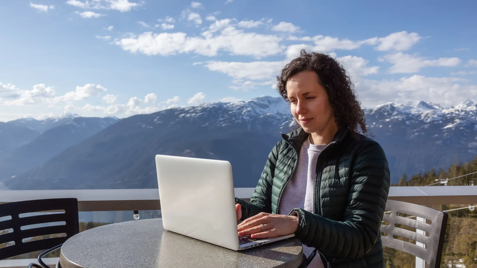 Woman digital nomad works on her laptop by the mountains in Canada