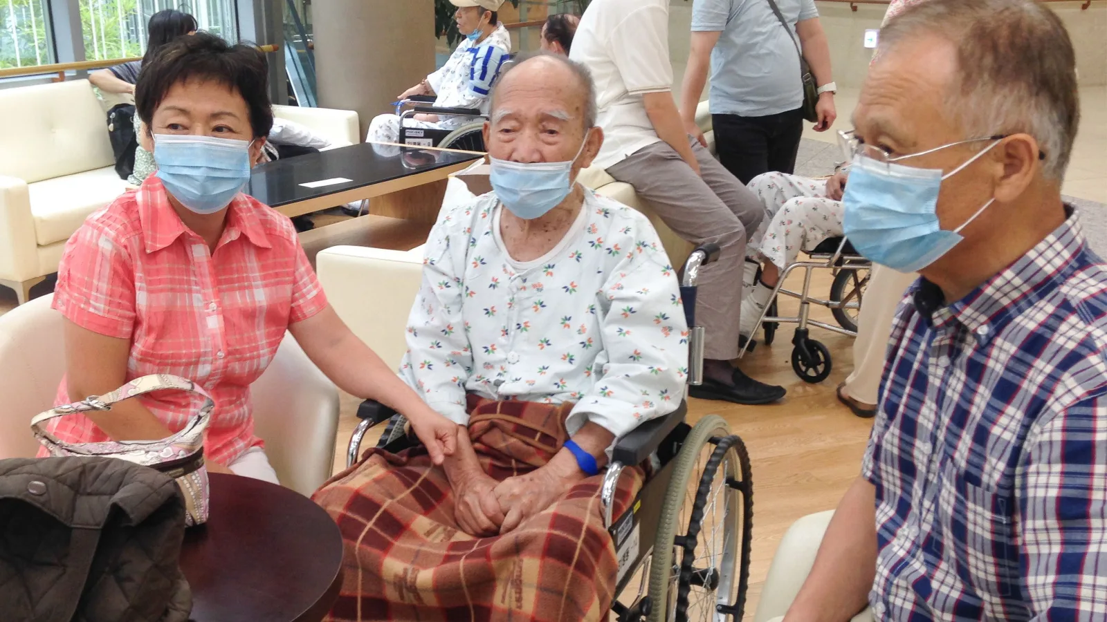 Three elder people in South Korea sit in chairs