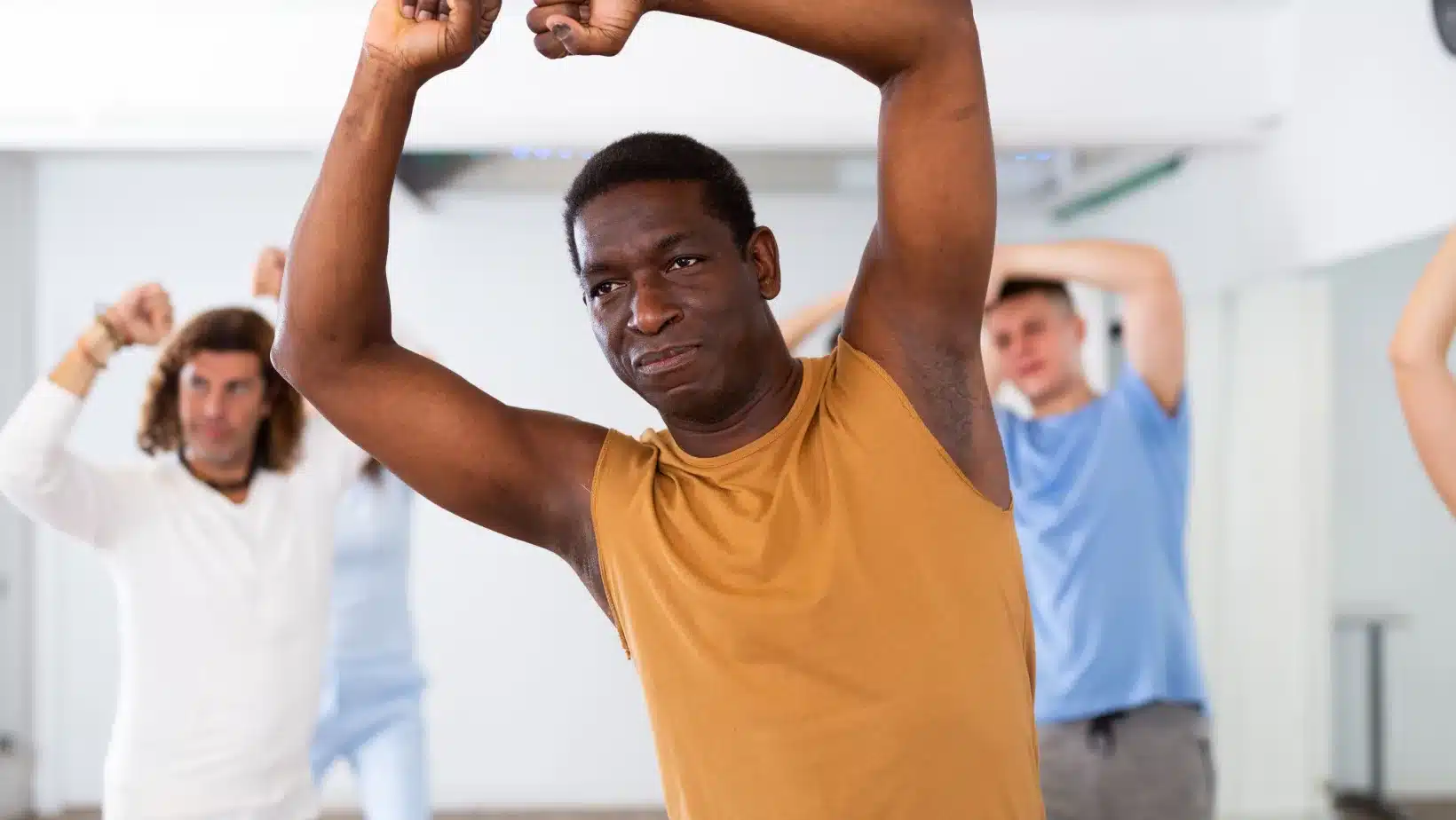 A Black man stretches with others during yoga class in Germany
