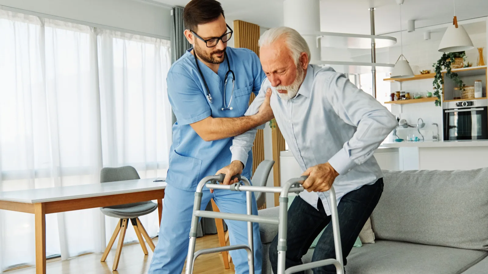 A nurse helping a man with a walker.