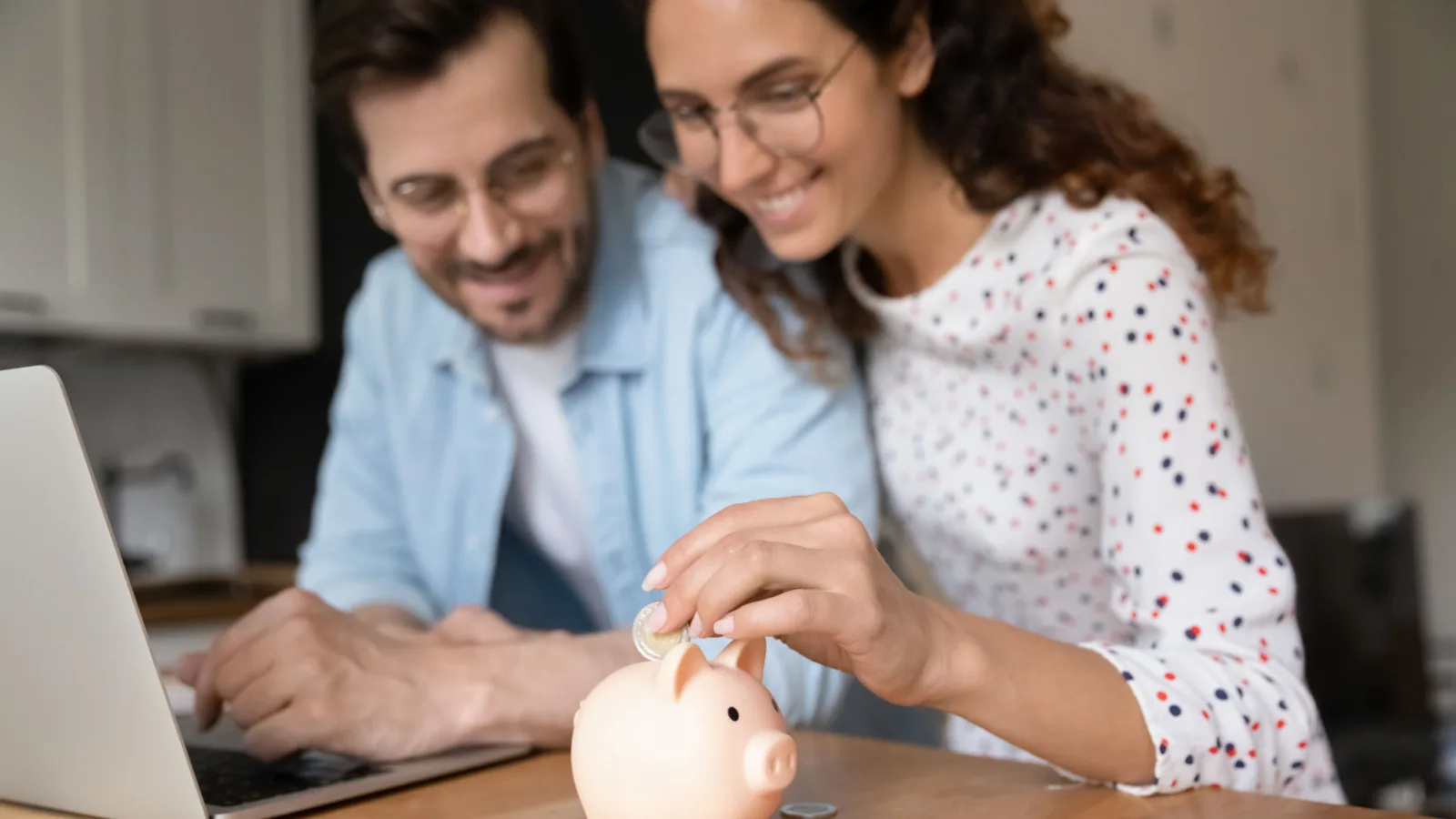 A couple putting money into a piggy bank.